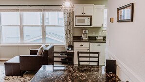 A modern kitchen with white cabinets, a microwave, and a coffee maker. There is a dining area with a marble table and chairs. - Bay Breeze across from Waterfront (Eureka)