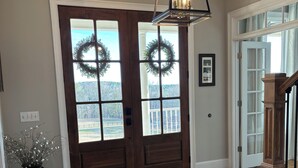 A spacious entryway with a wooden floor, a dark brown double door with glass panels, and a large chandelier. - SOUTHERN LIVING! Newly renovated! Private with Mountain views-sleeps 16 (Kingston)
