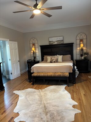 A bedroom with a large bed, a ceiling fan, a white door, and a cowhide rug. - SOUTHERN LIVING! Newly renovated! Private with Mountain views-sleeps 16 (Kingston)