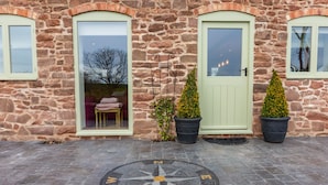 A stone building with three doors, each with a window above. There is a compass rose on the ground in front of the doors. - The Patches (Shrewsbury)