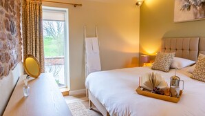 A hotel room with a bed, a bedside table with a mirror, a tray with a book, a coffee maker, and a window with curtains. - The Patches (Shrewsbury)