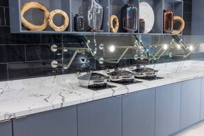 Una cocina con encimeras de mármol, una vitrina de vidrio con diversos utensilios de cocina y un salpicadero moderno.