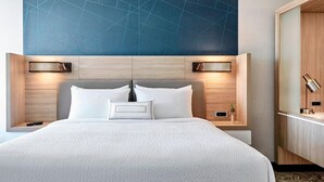 A modern hotel room with a large bed, two bedside tables, a nightstand, and a wall-mounted lamp. - SpringHill Suites by Marriott Slidell (Slidell)