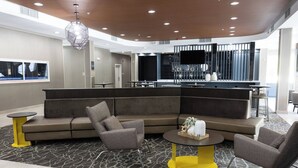 A modern lounge area with a sectional sofa, armchairs, a round coffee table, and a bar area in the background. - SpringHill Suites by Marriott Slidell (Slidell)