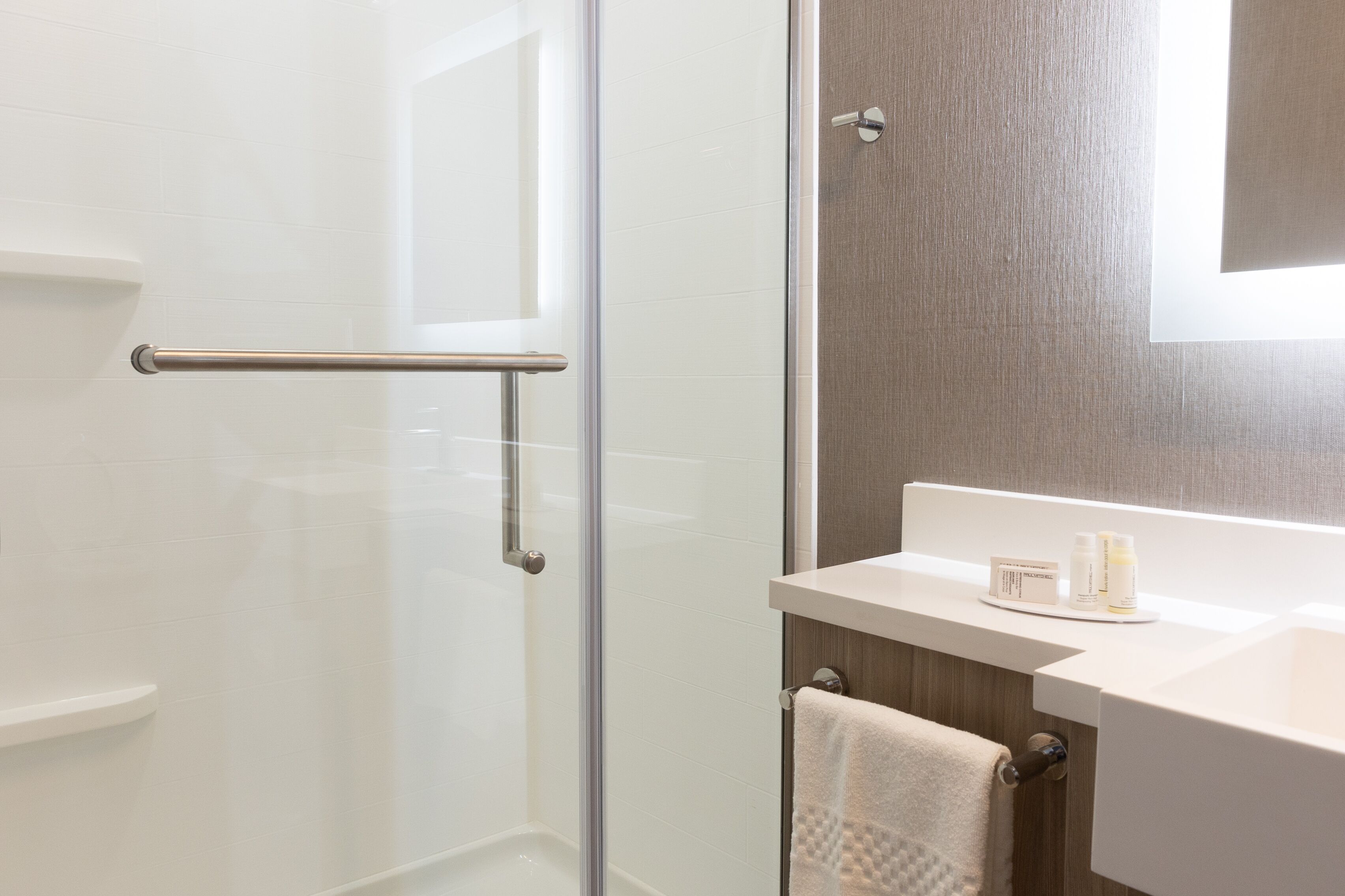A modern bathroom with a glass shower enclosure, a wooden vanity, and a towel rack.