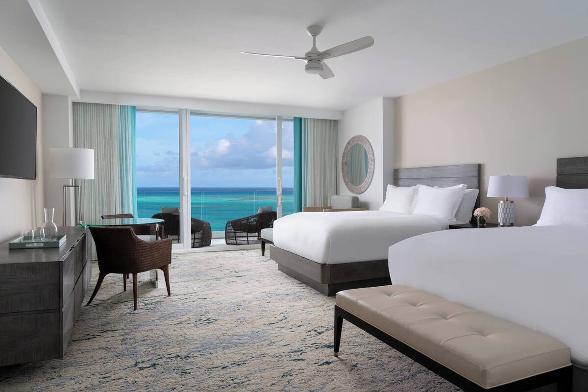 A hotel room with a large bed, a desk, a chair, and a view of the ocean.
