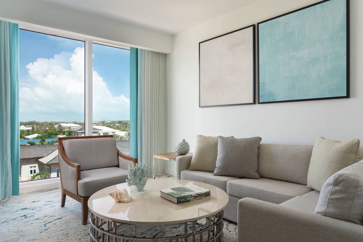 A modern living room with a large window, a sofa, a chair, and a coffee table.