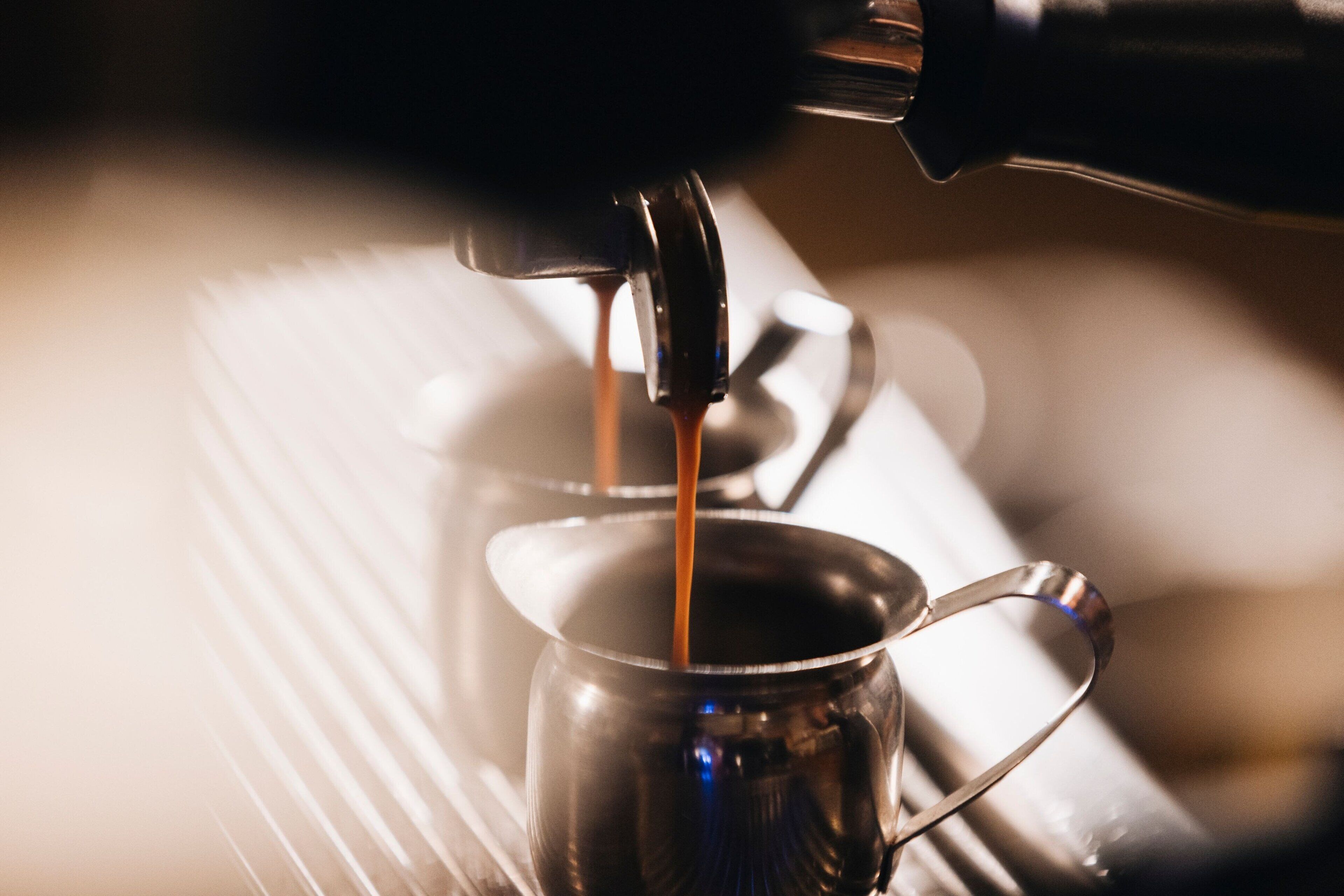 A close-up of a coffee machine dispensing coffee into a metal cup.