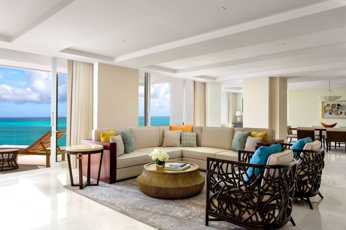 A spacious living room with a large sofa, a coffee table, and wicker chairs.
