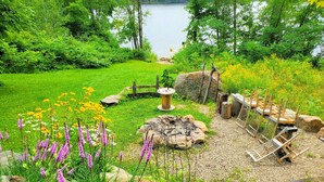 Un jardín con un estanque, asientos de madera y diversas plantas.