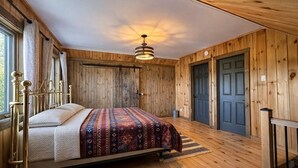 Una habitación con paneles de madera, una cama, una lámpara colgante y una puerta.