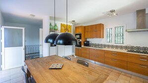 Une cuisine moderne avec des meubles en bois, une grande table à manger et des luminaires suspendus.