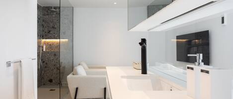 A modern bathroom with a glass shower enclosure, a white vanity, and a large mirror.