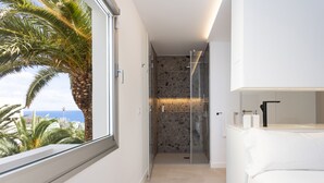 A modern bathroom with a glass shower, a white bathtub, and a view of the ocean through a large window. - Remote workers paradise @ the Atlantic  (Las Caletillas)