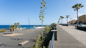 A coastal promenade with a wooden walkway, palm trees, and a view of the sea. - Remote workers paradise @ the Atlantic  (Las Caletillas)