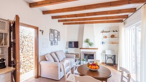 A cozy living room with a sofa, a dining table with fruit, and a fireplace. - Villa Pitaya Frigiliana by Ruralidays (Málaga)