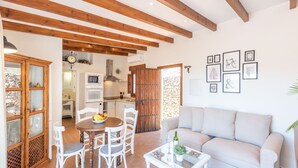 A spacious living area with a wooden ceiling, a dining table with chairs, a sofa, and a kitchen in the background. - Villa Pitaya Frigiliana by Ruralidays (Málaga)