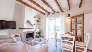 A living room with a fireplace, a television, and a dining area with chairs and a table. - Villa Pitaya Frigiliana by Ruralidays (Málaga)