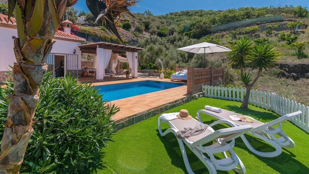 A private pool area with a pergola, lounge chairs, and a white picket fence. - Villa Pitaya Frigiliana by Ruralidays (Málaga)