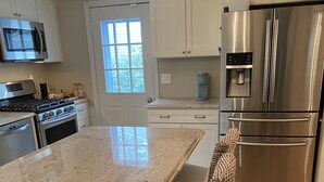 Una cocina moderna con encimeras de granito, electrodomésticos de acero inoxidable y una isla grande con taburetes de bar.