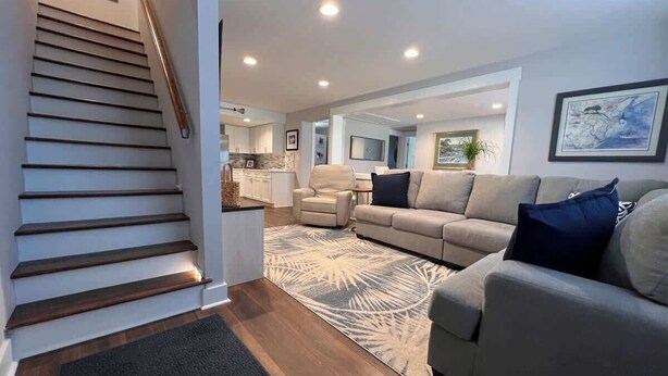 A modern living room with a staircase, a sofa, a coffee table, and a kitchen area in the background. - Oatland Island Family Cottage 10 minutes from Tybee Island and Historic Savannah (Savannah)