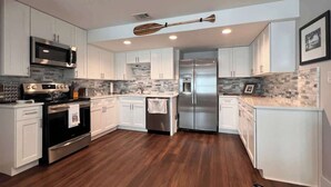A modern kitchen with white cabinetry, stainless steel appliances, and a wooden floor. - Oatland Island Family Cottage 10 minutes from Tybee Island and Historic Savannah (Savannah)