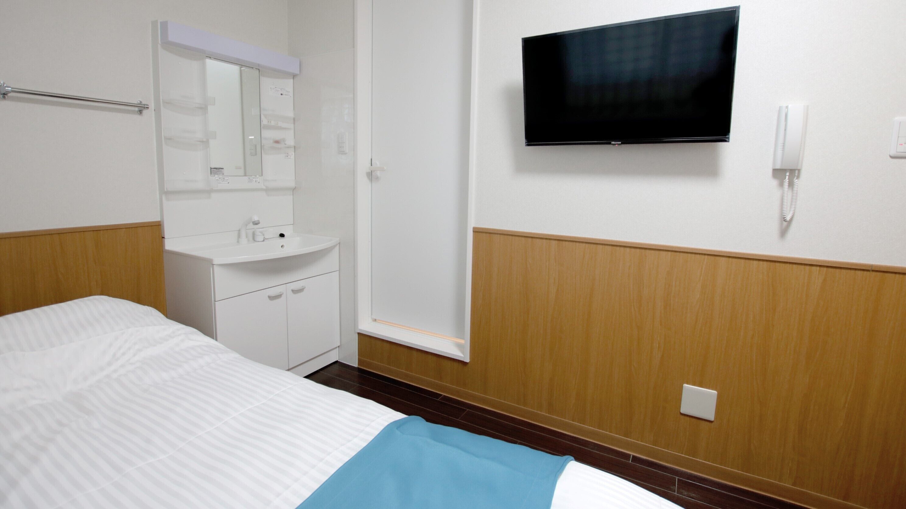 Habitació d'hotel amb llit, tauleta de nit, mirall, televisió i telèfon.