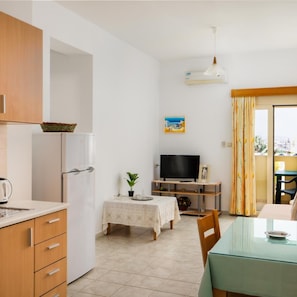A compact living space with a kitchenette, a dining area, and a TV. - Fotis Studios Apartments (Hersonissos)