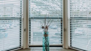 Une fenêtre en saillie ornée d’un vase contenant des branches séchées sur le rebord.