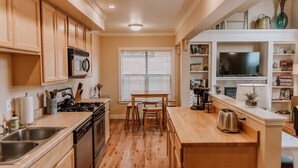 Une cuisine moderne avec des meubles en bois, un four à micro-ondes encastré, une cuisinière et un coin repas comprenant une table et des chaises.