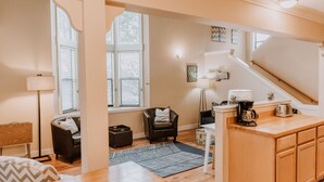 Un salon moderne comprenant un canapé, un fauteuil, une table basse et un escalier menant à un niveau supérieur.