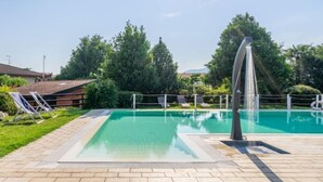 Una piscina con sillas de descanso y una fuente de agua.
