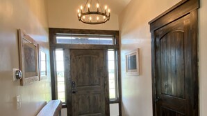 A hallway with a wooden bench, a large wooden door, and a chandelier. - Beautiful Family Getaway with Breathtaking Teton Views (Tetonia)