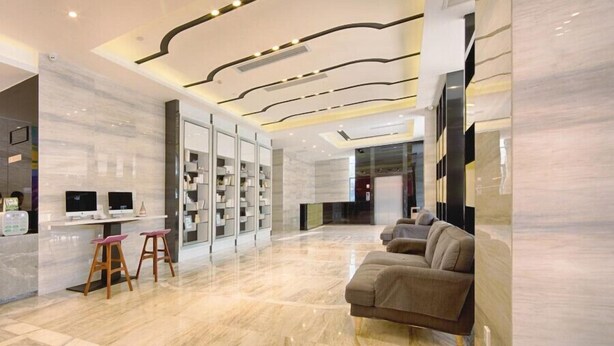 A modern lobby with a marble floor, a reception desk, a sofa, and a seating area with stools. - Lavande Hotel - Guangzhou Panyu Chimelong (Guangzhou)