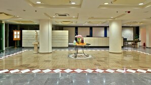A spacious lobby with a marble floor, a reception desk, and a decorative table with flowers. - Minos All Suites (Rethymno)