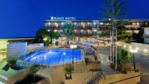 A hotel with a swimming pool, outdoor seating, and a well-lit facade. - Minos All Suites (Rethymno)