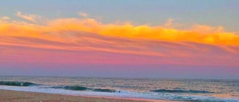 Ein Strand mit Wellen und einem Sonnenuntergangshimmel.