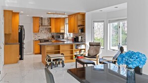 Une cuisine moderne avec des meubles en bois, un îlot central et un coin repas comprenant une table et des chaises.