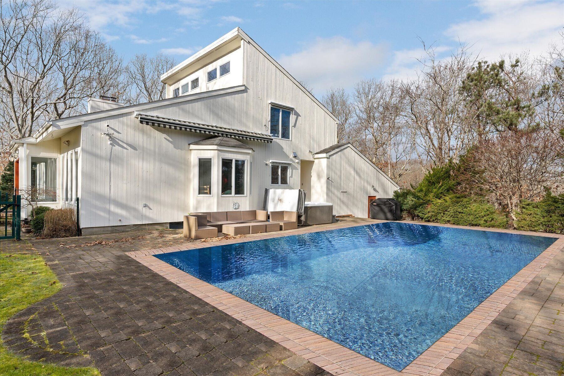 A modern two-story house with a rectangular swimming pool.