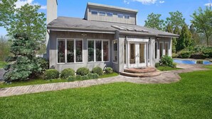 Une maison à deux étages dotée d’un patio couvert, d’une piscine et d’une pelouse bien entretenue.