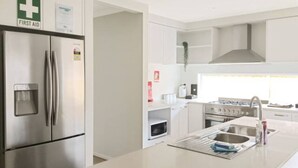 A modern kitchen with stainless steel appliances, a built-in microwave, and a large island with a sink. - New Torquay Beaches Deakin Uni Hospitals (Armstrong Creek)