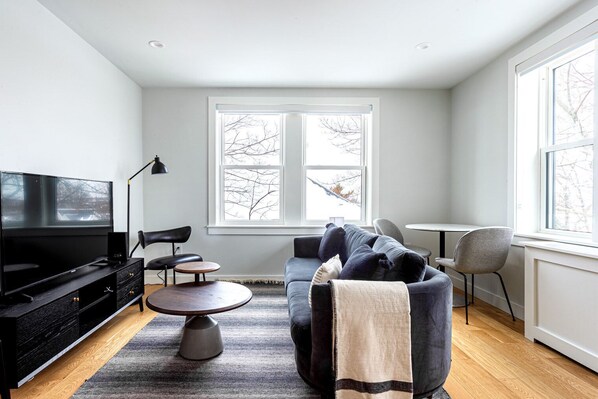 Relax in this stylish living room with a large flat-screen TV, comfortable seating, and a cozy coffee table.