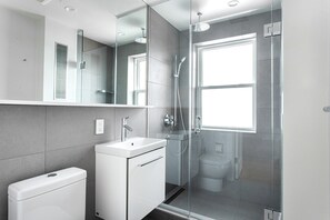 Enjoy a sleek bathroom with a glass-enclosed shower, sink, and compact storage.