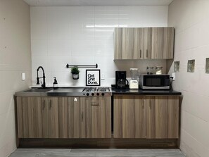 A compact kitchen with a sink, stove, microwave, and coffee maker. - Spacious 8-bedroom House in Central Guadalajara (Guadalajara)