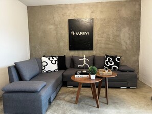 A modern living room with a grey sectional sofa, a wooden coffee table, and a minimalist decor including a wooden mannequin and a small plant. - Spacious 8-bedroom House in Central Guadalajara (Guadalajara)