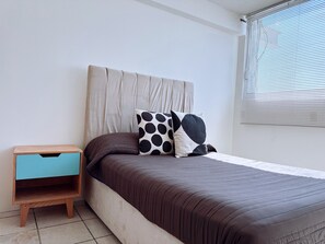 Un dormitorio con cama, mesita de noche y ventana con persianas.