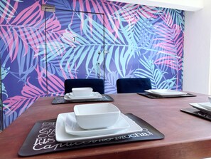 A conference room with a table set for a meeting, featuring a tropical leaf pattern on the wall and a black placemat with the text "Espresso Mocha". - Spacious 8-bedroom House in Central Guadalajara (Guadalajara)