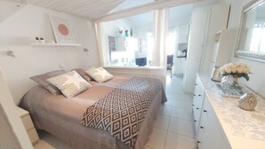 Una camera da letto con un letto, una cassettiera, uno specchio e una finestra.