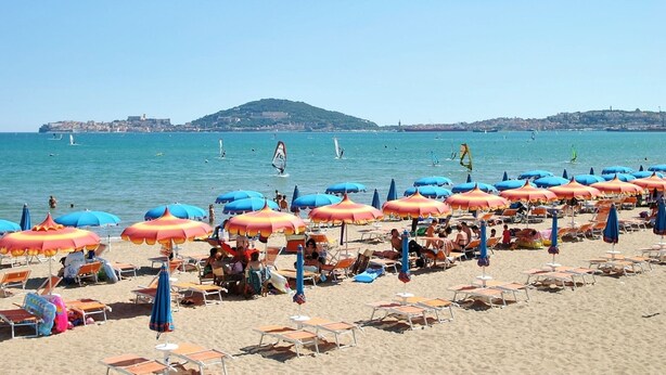 A beach with rows of sun loungers and umbrellas, a clear sky, and sailboats on the water. - Dinky Home Air-conditioned Penthouse With sea View Terrace (Formia)