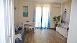 A living room with a sofa, dining table, chairs, and a TV. - Dinky Home Air-conditioned Penthouse With sea View Terrace (Formia)